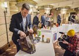 Representative Daudt and Representative Lee compete to put grocery items into a reusable bag. In front of the table where Representative Daudt is working, a photographer kneels to record a video of him.