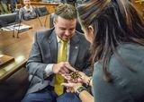 Representative Heintzeman uses a finger to pet a tarantula being held by a woman.