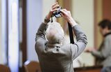 Representative Sandell holds his camera up over his head to take a photo.