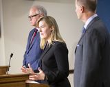 House Speaker Melissa Hortman stands behind a podium and speaks to someone out of view. Governor Walz stands on one side of her, and Senate Majority Leader Paul Gazelka stands near her on the other side.