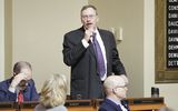 Representative Nelson stands at his desk in the House Chamber and speaks to someone out of view using a microphone.
