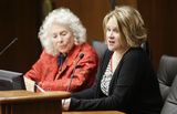 Cindy Rourke sits at the testifiers' table and speaks to someone out of view. Representative Murphy sits next to her.