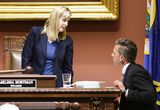 Speaker Melissa Hortman stands behind the Speaker's podium and speaks to Minority Leader Kurt Daudt, who stands beside the podium.