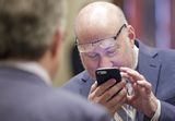 Representative Hornstein holds his cell phone close to his face to look at something. His glasses rest above his eyes.
