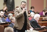 Representative Lillie stands at his desk in the House Chamber and holds a microphone while speaking to someone out of view.
