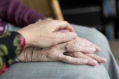 Health care worker's hand on elderly hand